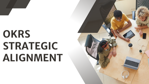 OKRs strategic alignment concept showing a project team collaborating around a table with laptops and digital tools.